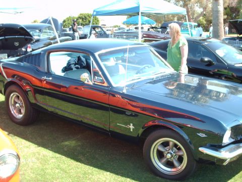 1992 Ford Bronco - A classic Mustang is parked on the grass at an outdoor car show, with other vehicles visible.
