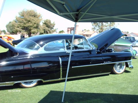 1992 Ford Bronco - A classic black Cadillac is displayed with its hood open at an outdoor event, with other vehicles in the background.