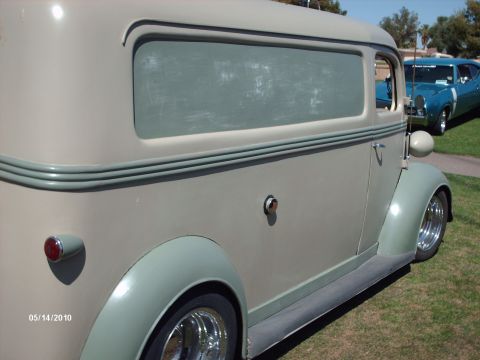 1992 Ford Bronco - A vintage panel van is parked on grass next to a blue car at an outdoor event.