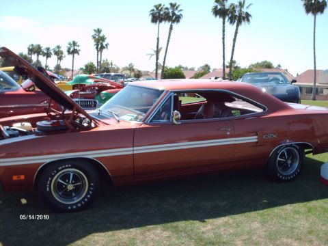 1992 Ford Bronco - A classic orange muscle car with dual white side stripes and a GTX emblem is displayed at an outdoor car show.