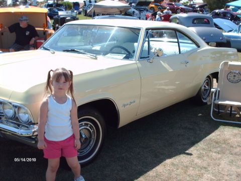 1992 Ford Bronco - A young girl poses in front of a pale yellow coupe at a car show, with other vehicles visible in the background.