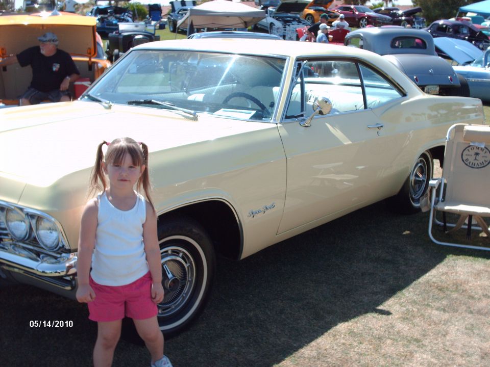 Pale yellow 1965 coupe with a young girl standing in front
