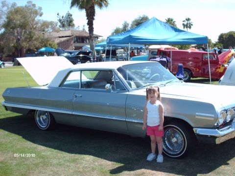1992 Ford Bronco - A young girl stands next to a classic 1963 Chevrolet Impala at a car show.