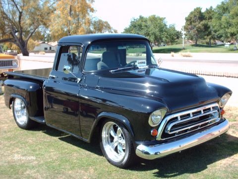 1992 Ford Bronco - This customized black Chevrolet pickup truck, likely from 1955, features a prominent hood scoop and chrome wheels.