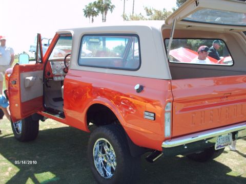 1992 Ford Bronco - This orange Chevrolet K5 Blazer features a tan removable top and chrome wheels, seen at a car show.