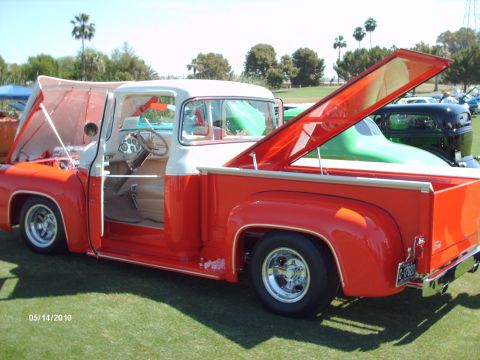 1992 Ford Bronco - A classic red and white pickup truck is displayed with its hood and tonneau cover open at an outdoor car show.
