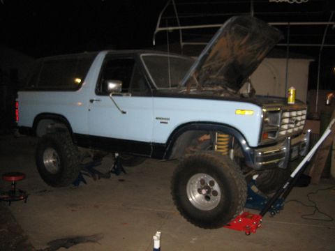 1986 Ford Bronco - This lifted Ford Bronco appears to be undergoing maintenance with its hood open and supported by jack stands.