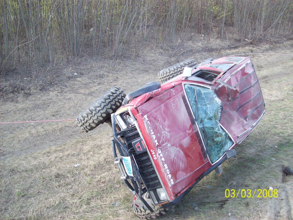 Red Jeep rolled onto its side with 'Kodiak Off-Road' text visible