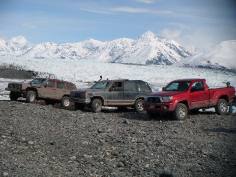 1998 Jeep Cherokee - A convoy of four-wheel-drive vehicles, including a 1998 Jeep Cherokee, navigates a rocky landscape beneath snow-covered peaks.