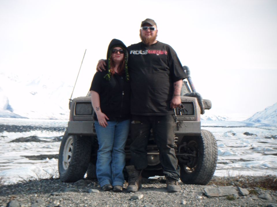 Couple in front of a 1998 Jeep Cherokee with off-road modifications in a snowy, icy landscape