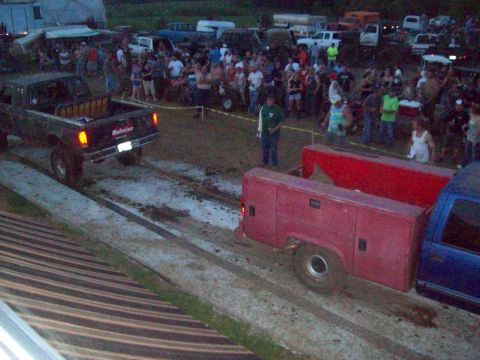 2005 Ford Excursion - A truck pulls a trailer through a muddy track while spectators watch.