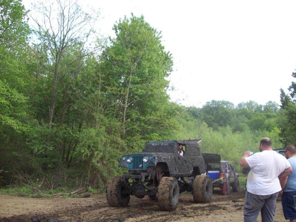 Mud-covered Jeep with large tires, front view