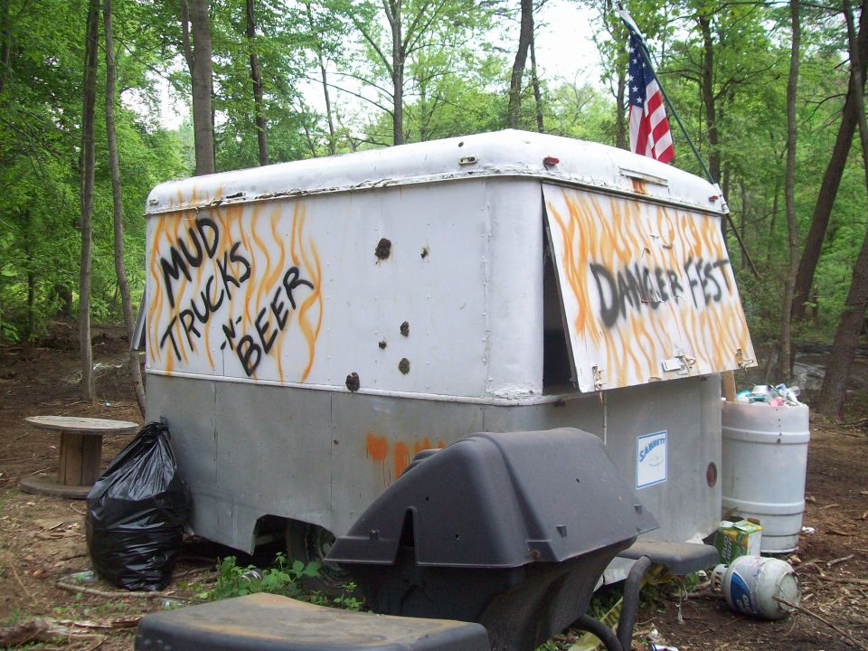 White trailer with graffiti, bullet holes, and an American flag
