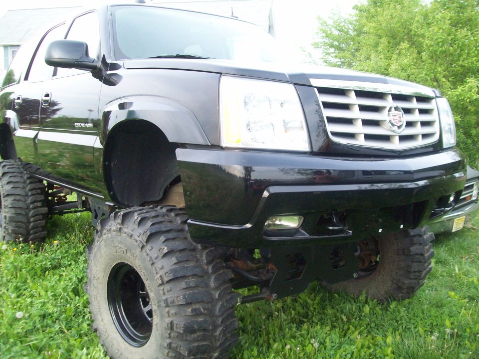 Black lifted Cadillac Escalade with large off-road tires, front quarter view