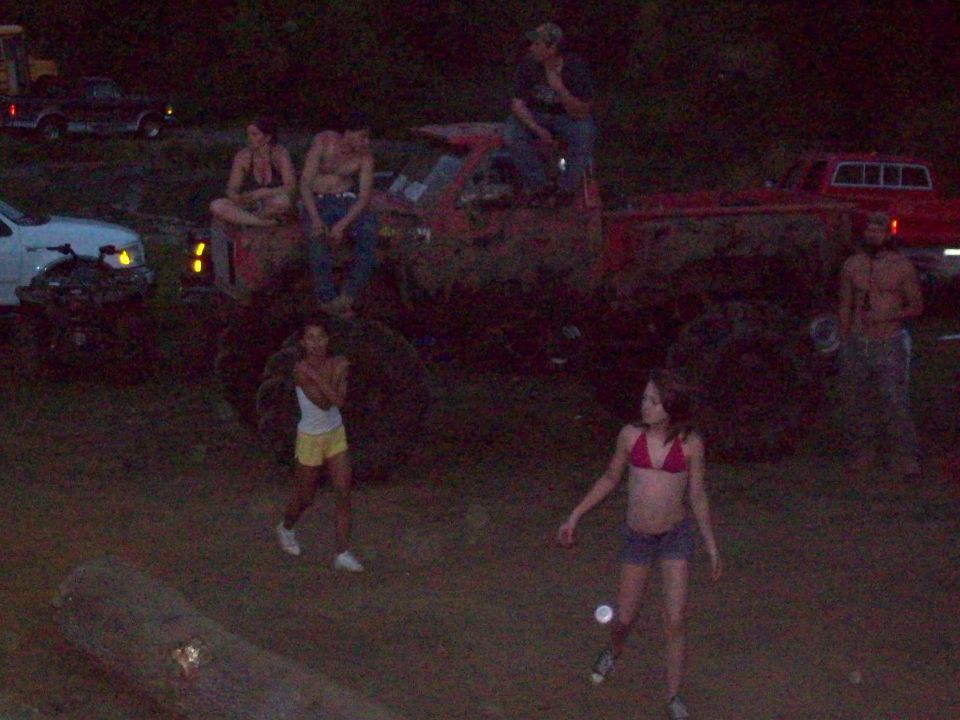 Muddy red truck with people gathered around at night