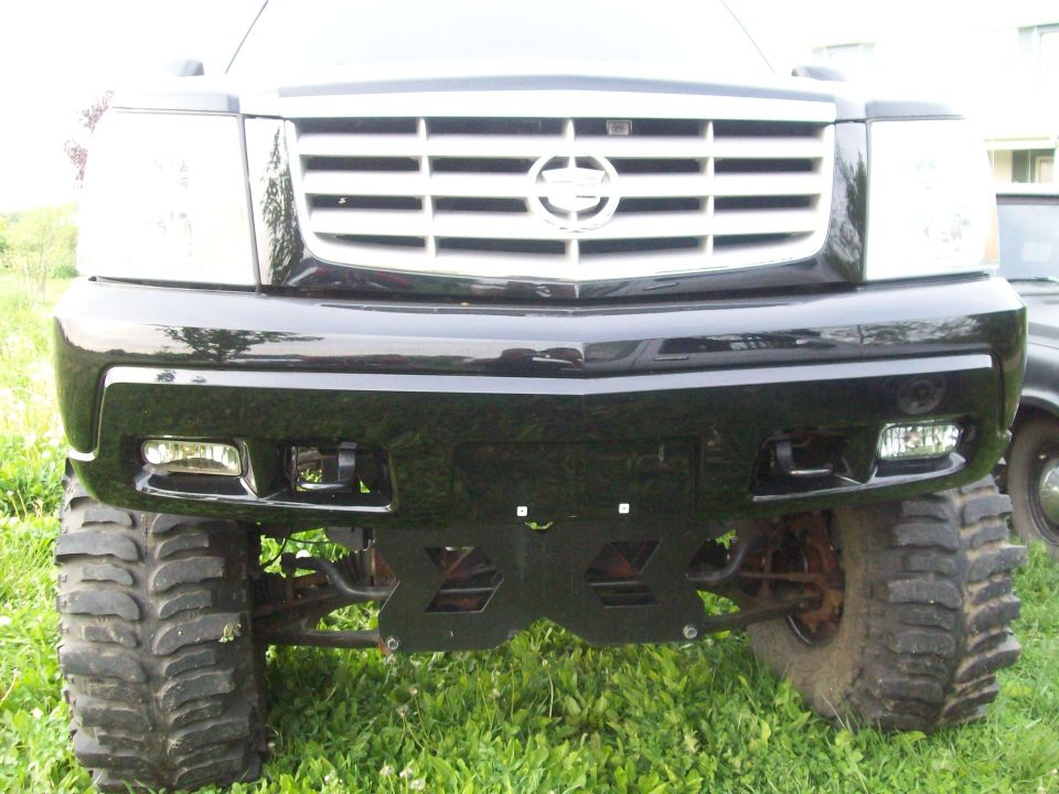 Front view of a lifted black Cadillac Escalade with large tires and a chrome grille