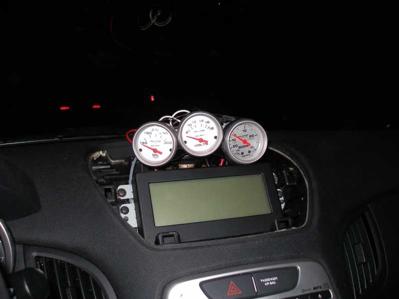 Three gauges on car dashboard: oil pressure, volts, and boost