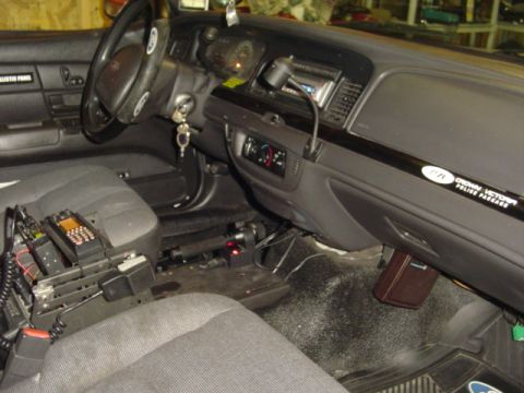 2003 Ford Crown Victoria - The interior of a 2003 Ford Crown Victoria police car, equipped with radios and other law enforcement gear.
