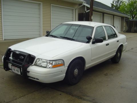 2003 Ford Crown Victoria - White 2003 Ford Crown Victoria police car parked in front of a garage.