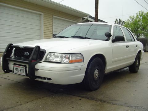 2003 Ford Crown Victoria - This 2003 Ford Crown Victoria police car is equipped with a push bumper and parked in front of a residential garage.