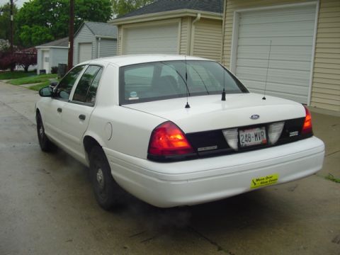 2003 Ford Crown Victoria - Rear view of a white 2003 Ford Crown Victoria, a black accent panel and a yellow bumper sticker.