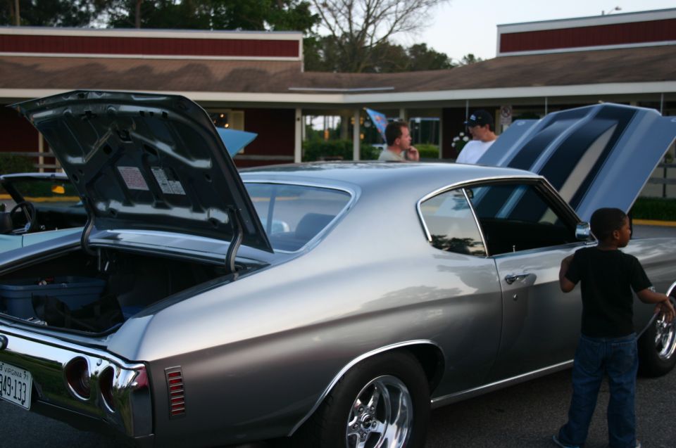 Silver muscle car with hood and trunk open. A kid stands by the passenger door