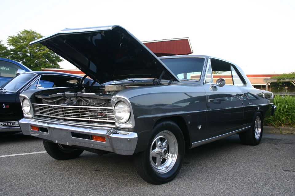 Dark gray 1967 Chevrolet Nova SS coupe with hood open, parked next to a black car