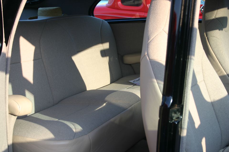 Car interior with light-colored seats and a red car visible through the window