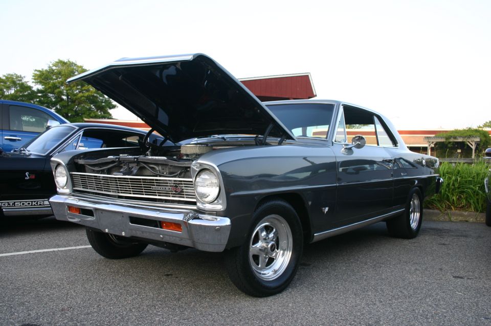 1967 Chevrolet Nova with hood open, parked next to a blue truck