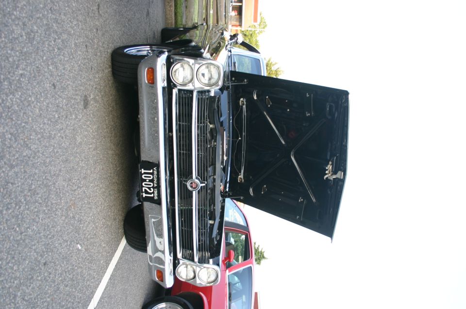 1968 Ford Mustang front view with hood open, showing engine bay. License plate reads 10-021