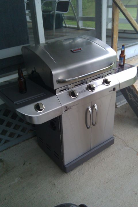 1966 Ford Five Hundred - A stainless steel grill sits on a concrete patio, with two beer bottles placed on its side shelves.