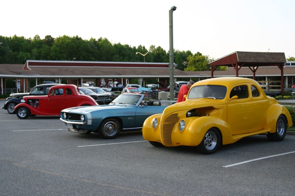 Yellow coupe with hood open, parked at a car show