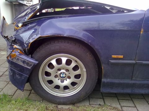 1998 BMW 3 Series - The front passenger side of a damaged blue 1998 BMW 3 Series shows significant front-end collision damage.