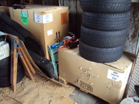 1993 Ford Probe - A collection of tires and boxes are stored in a cluttered garage or workshop area.