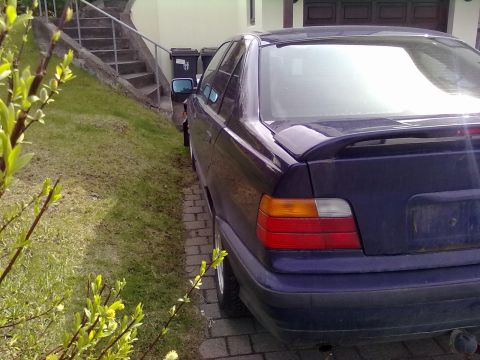 1998 BMW 3 Series - Rear view of a dark purple 1998 BMW 3 Series sedan with a spoiler, parked on a brick driveway.
