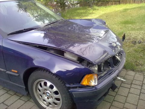 1998 BMW 3 Series - The front of a blue BMW 3 Series shows severe damage to the hood and front bumper area.