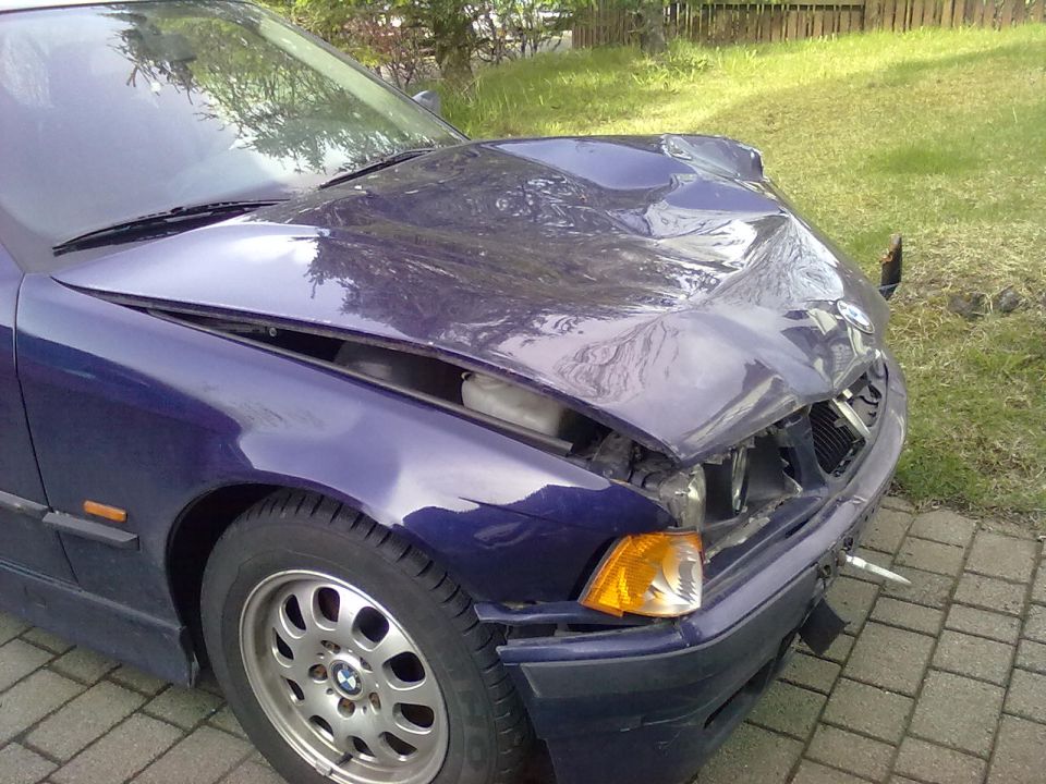 Front end of a blue BMW 3 Series with significant hood and bumper damage