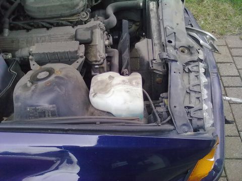 1998 BMW 3 Series - The engine bay of a blue 1998 BMW 3 Series shows the coolant reservoir and radiator assembly.
