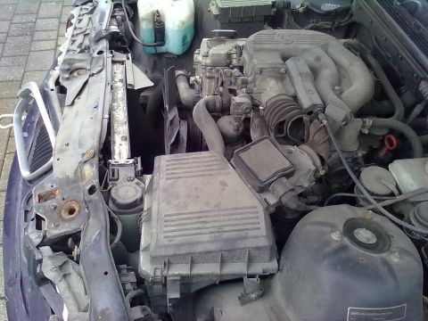 1998 BMW 3 Series - The engine bay of a vehicle, showing various components including the air intake system and hoses.