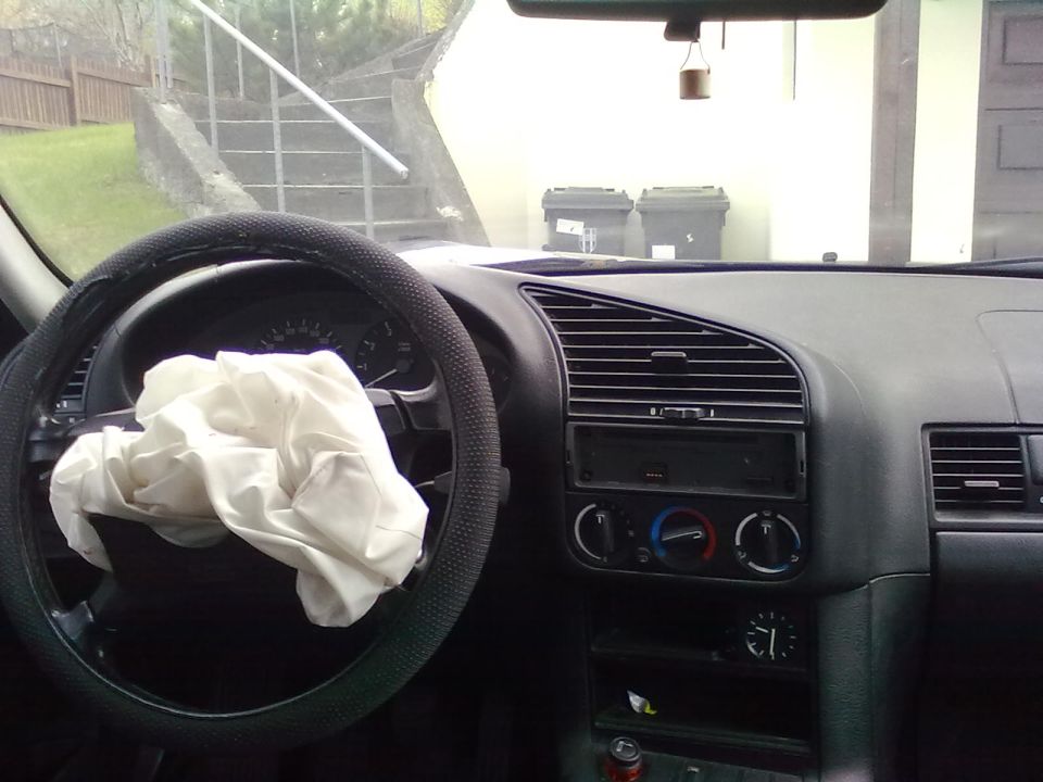 BMW 3 Series interior with a deployed driver airbag over the steering wheel