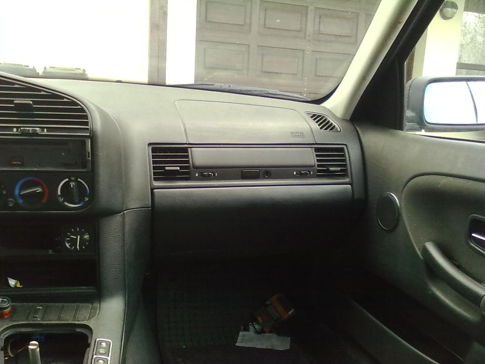Black BMW dashboard interior view with center vents, analog clock and manual shifter