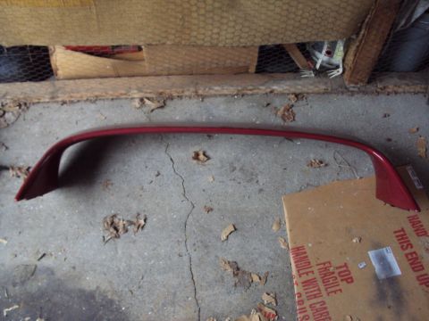 1993 Ford Probe - A red car spoiler lies on a concrete floor, with debris scattered around.