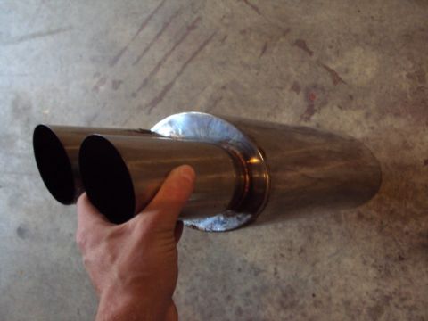 1993 Ford Probe - A person holds a chrome dual exhaust tip, likely an aftermarket part, against a concrete background.