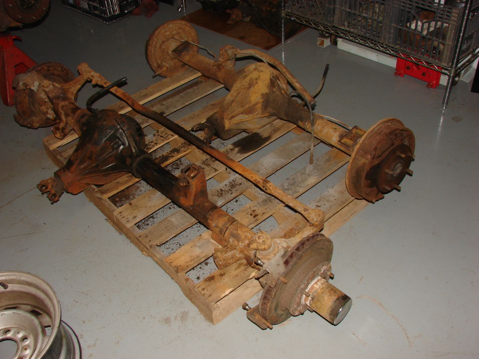 Two rusty vehicle axles on a wooden pallet