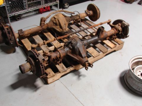 1993 Jeep YJ - Two heavily rusted vehicle axles are displayed on a wooden pallet, likely for sale or storage.