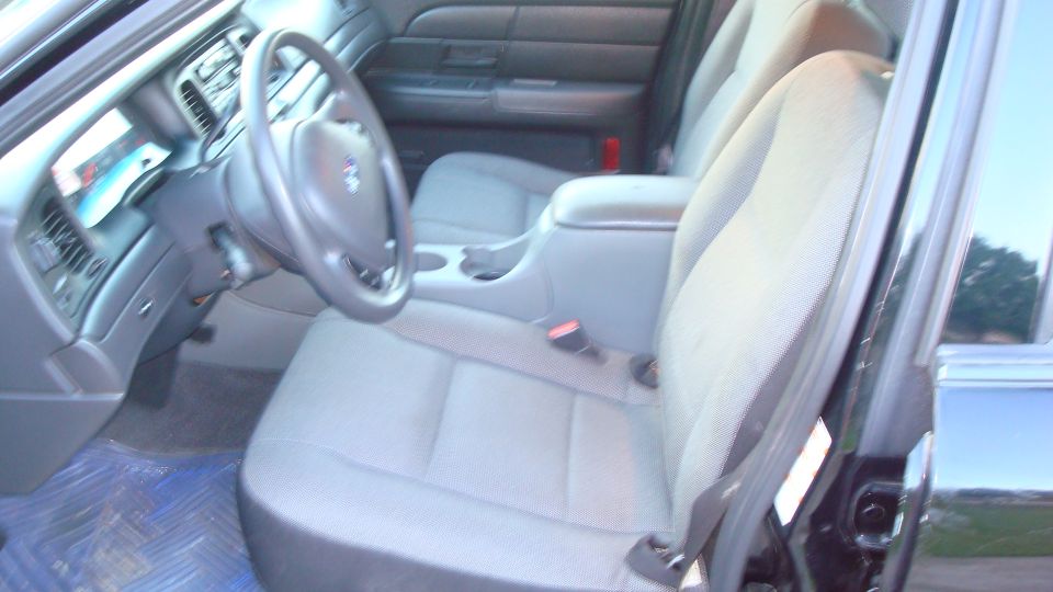 Car interior with cloth seats, steering wheel, and dashboard visible