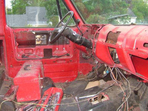 1985 Chevrolet C/K Pickup - The dashboard and interior of a red truck are disassembled, revealing exposed wiring and tools.