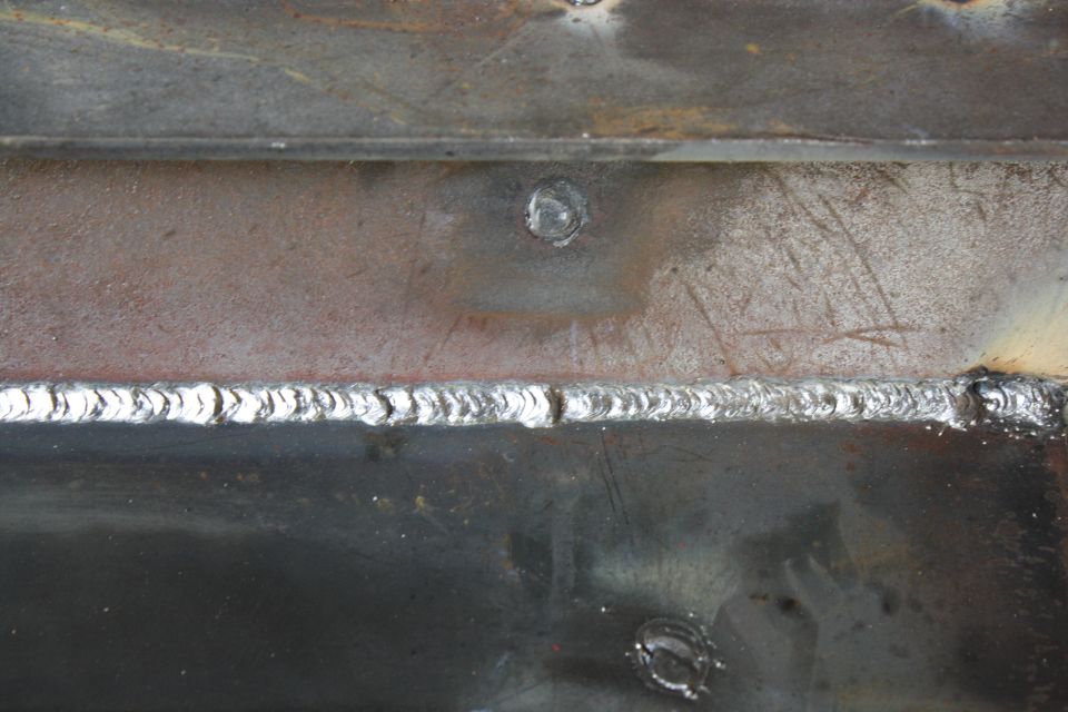 Welded metal frame with visible weld beads and a bolt head