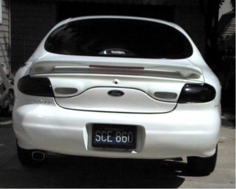 1997 Ford Taurus - Rear view of a white 1997 Ford Taurus sedan, tinted taillights and a rear spoiler.