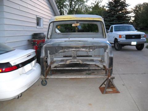 1954 Ford F-100 - Truck cab being worked on, with another truck and car nearby.